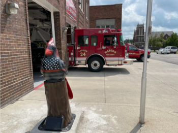 A cardinal statue stands in front of a Fire Dept.