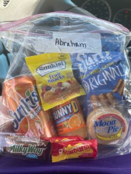 A eclipse-themed snack pack containing Sunkist orange soda, Sunkjist fruit snacks, Sunny Delight, Starburst candy, a Milky Way bar, a Moon pie and Sun chips. 