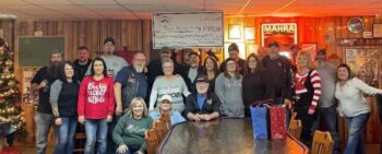 A group smiles around a large check. 