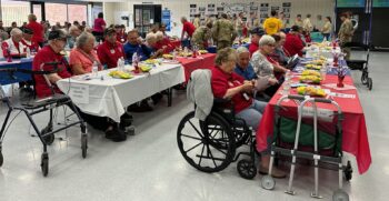Veterans sit at tables to be honored. These are senior men and women, some in wheelchairs and with walkers.