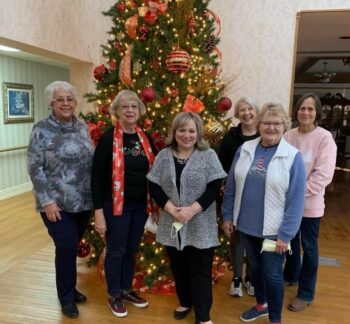 Volunteers smile in front of a Christmas tree. 