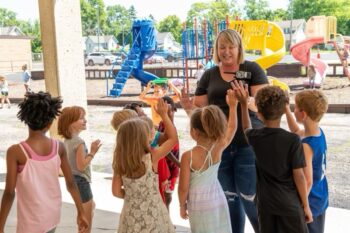 Maggie Breeding talks to kids outside the Oak Street Clubhouse. A playground is in the background. 