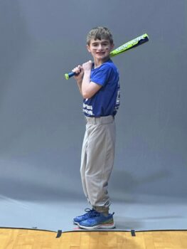 Luke wears a baseball uniform and poses with a bat .