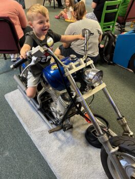 A boy has fun pretending to ride a motorcycle at the Explore-It-Torium. 