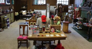 Tables and shelves display many items including shirts, jewelry, mugs, hats and more. It is now located inside the Explore-It-Torium. 