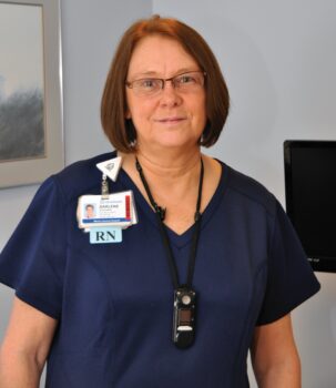 Darlene is a white woman with short brown hair and navy scrubs.