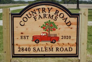 A wooden sign with a red truck Country Road Farms logo and "Est. 2020"