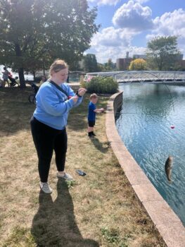 Kids fishing on the Marion campus pond. One girl has reeled in a small fish. 