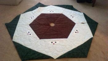 A white, green and red tree skirt with small snowman faces.