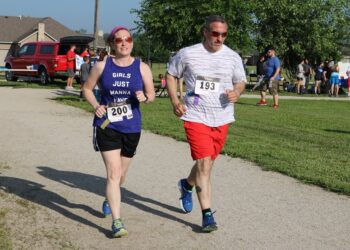 A man and a woman run around campus. 