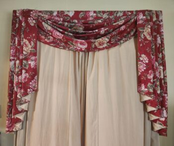 A handmade window covering in a red rose pattern.