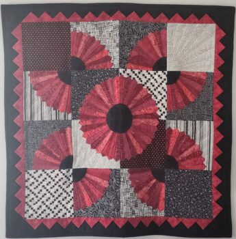 A red, cream and black quilt with flowers and geometric patterns