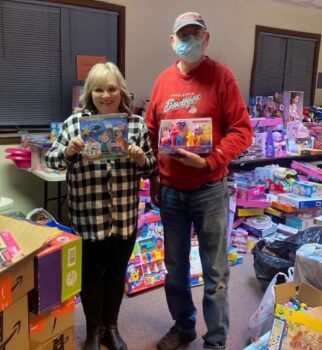 Two volunteers hold toys with many others in the background