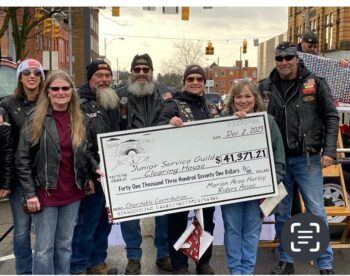 A motorcycle club presents a check for $41,371 to the director of the Christmas Clearinghouse at the Peanut Push.