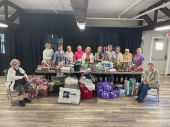 A group of women smiel around a large group of donated items.