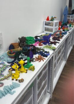 A long display of 3-D printed items includes giraffes, octopi, dragons and dice rolling towers.