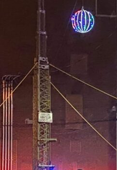 A large lighted ball hangs from a tower.