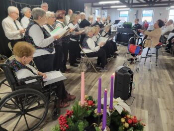 A group of seniors in matching vests and ties sing. 