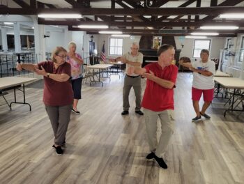 A group of seniors move slowly with their arms extended.