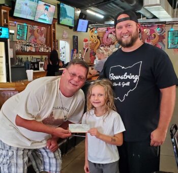 Matt Dowds smiles while presenting a check to a small girl and another man for the Easter event. 