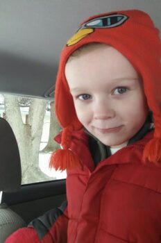 A smiling boy with an angry bird hat and red coat. 